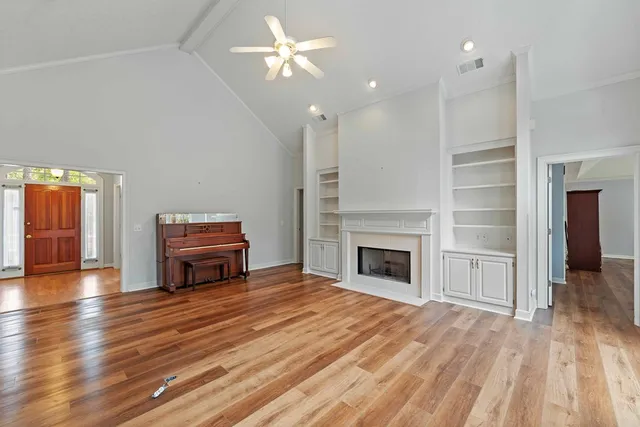 an empty room with wooden floor fireplace and windows