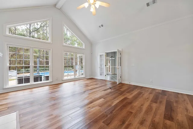 a view of an empty room with wooden floor and a window