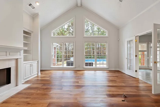 a view of an empty room with wooden floor and a window