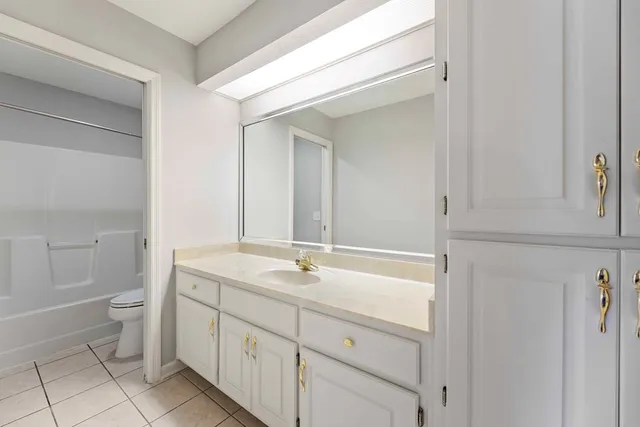 a spacious bathroom with a granite countertop sink a toilet and a mirror