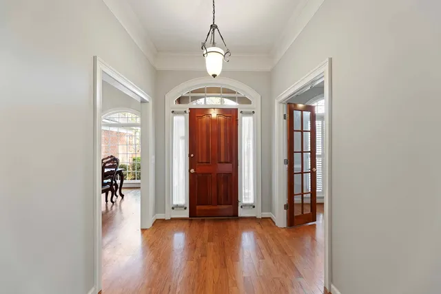 an empty room with wooden floor staircase and windows