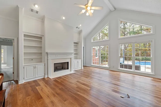 a view of an empty room with a window and wooden floor