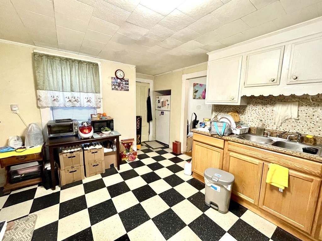 68 Smith Street Lowell, MA 01851 - Photo 16 of 24 a kitchen with a checkered floor and white cabinets