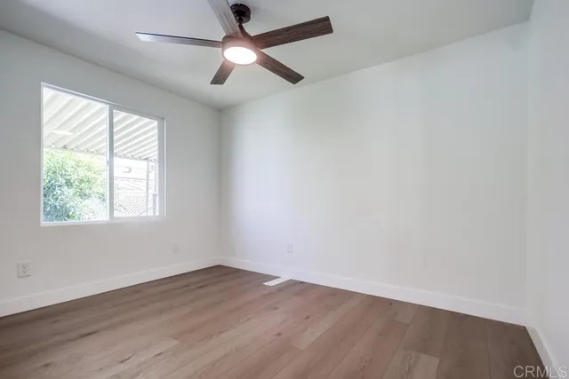an empty room with wooden floor fan and windows