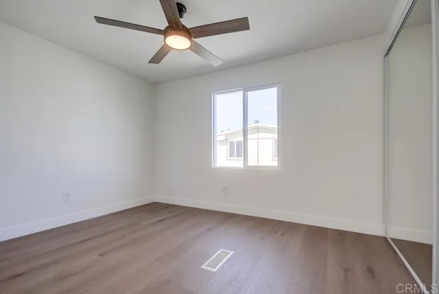 an empty room with wooden floor fan and windows