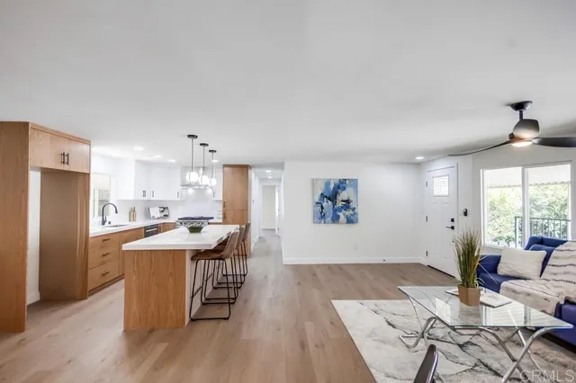 a living room with stainless steel appliances kitchen island a table and chairs in it