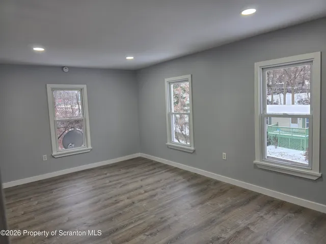 a view of an empty room with a window and wooden floor