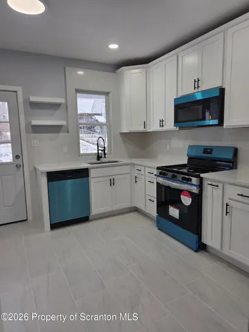 a kitchen with stainless steel appliances granite countertop a stove a sink and a microwave