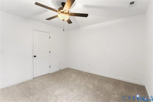 an empty room with a ceiling fan and carpet
