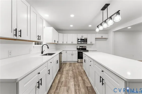 a large white kitchen with lots of counter space a sink and stainless steel appliances