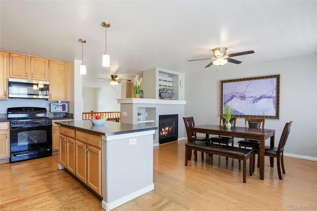 a open kitchen with stainless steel appliances granite countertop a stove top oven a sink a dining table and chairs with wooden floor