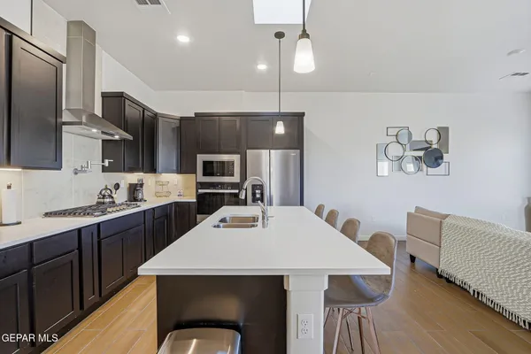 a kitchen with stainless steel appliances a dining table chairs refrigerator and cabinets