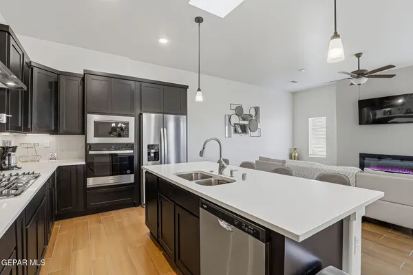 a kitchen with stainless steel appliances kitchen island granite countertop a sink a stove and refrigerator