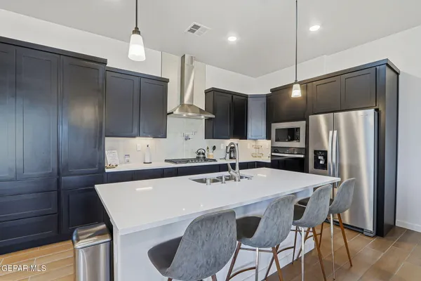 a kitchen with stainless steel appliances kitchen island granite countertop a table chairs microwave and refrigerator