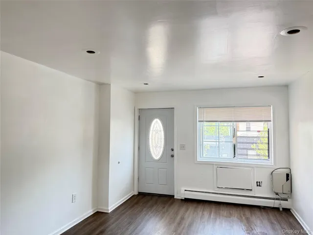an empty room with wooden floor and window