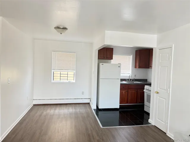 an empty room with wooden floor cabinet and windows