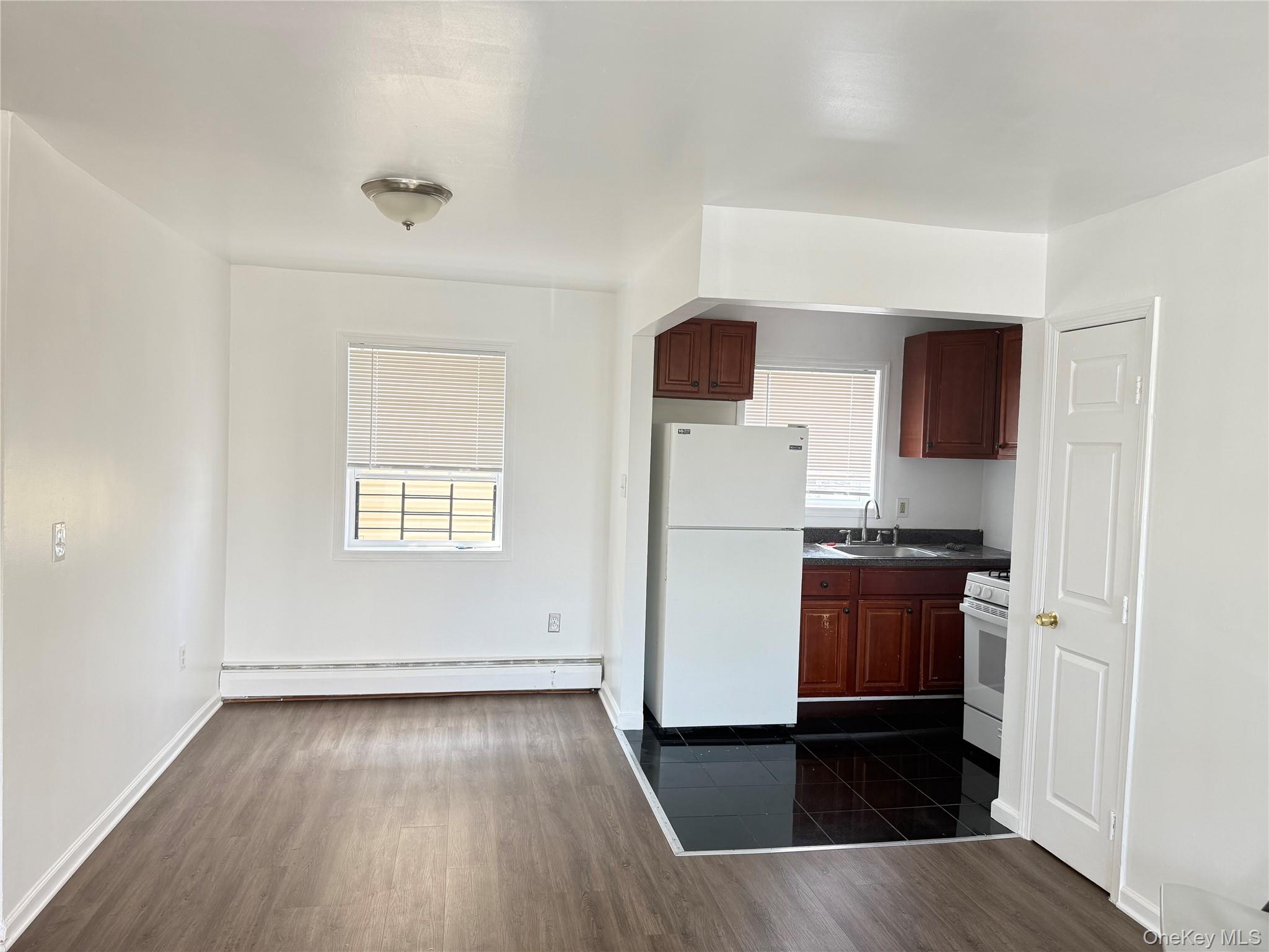 97-56 101st Street Queens, NY 11416 - Photo 4 of 17 an empty room with wooden floor cabinet and windows