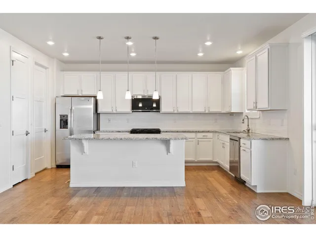 a kitchen with stainless steel appliances kitchen island granite countertop a stove a sink a refrigerator and white cabinets