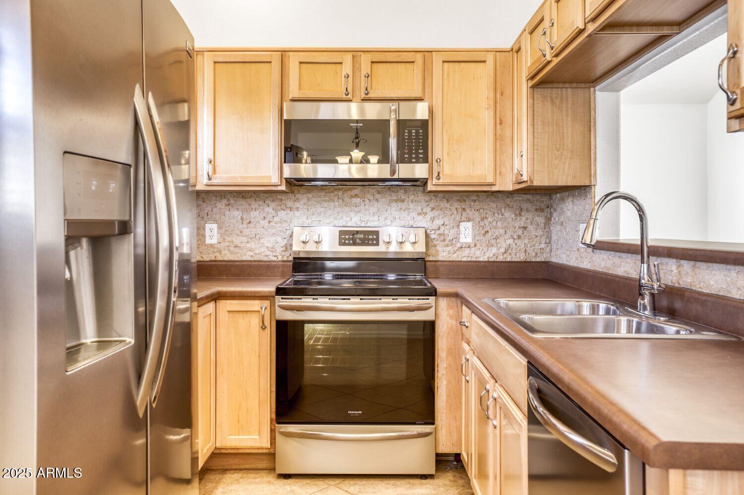 7101 West Beardsley Road, Unit 1403 Glendale, AZ 85308 - Photo 12 of 40 a kitchen with stainless steel appliances granite countertop a sink a stove and a refrigerator with cabinets