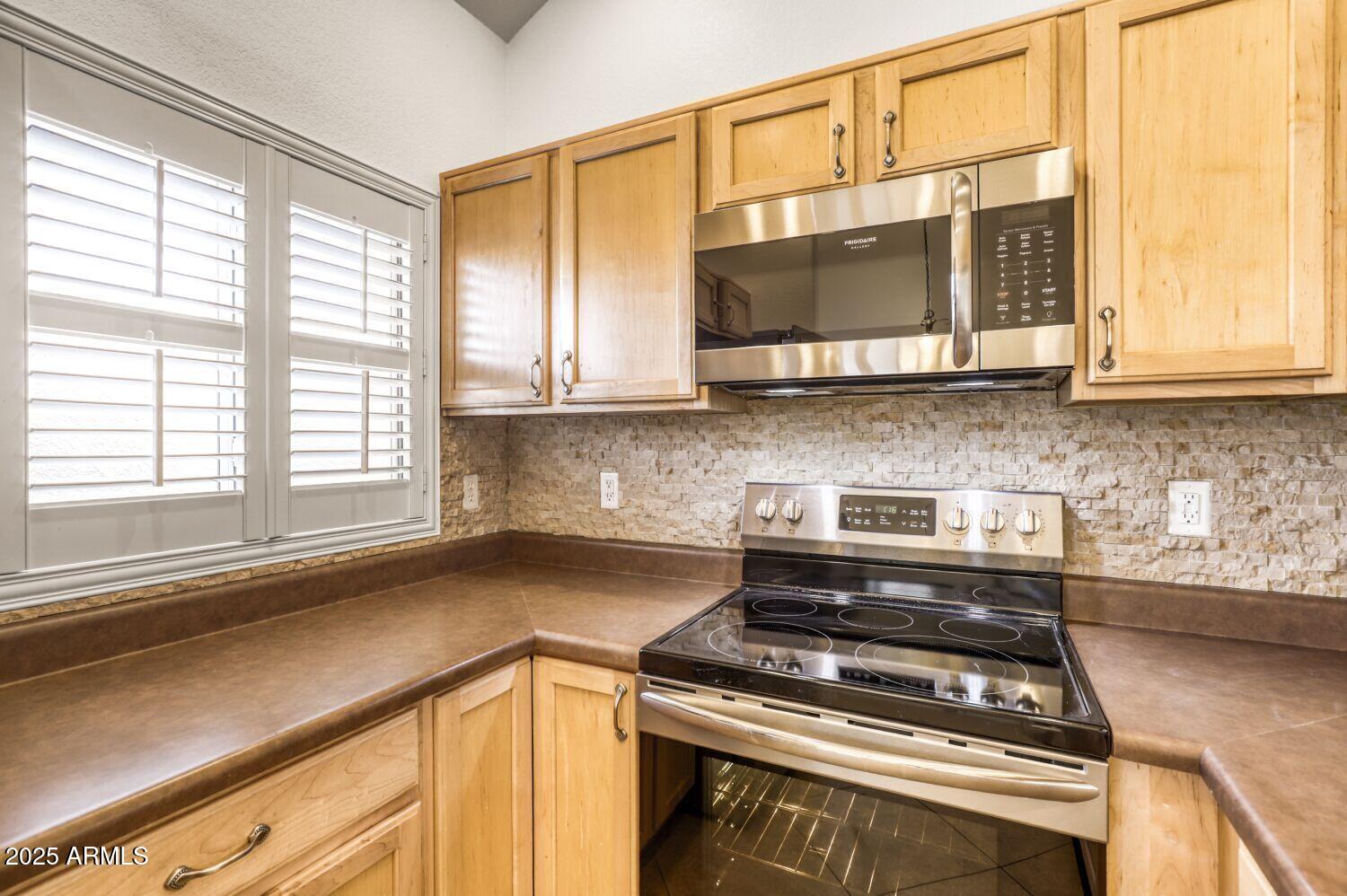 7101 West Beardsley Road, Unit 1403 Glendale, AZ 85308 - Photo 15 of 40 a kitchen with stainless steel appliances granite countertop a stove and a microwave