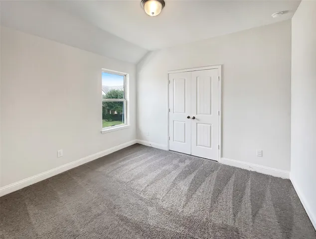 a view of an empty room with window and closet area