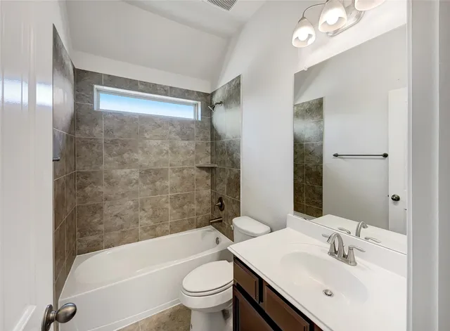 a bathroom with a bathtub shower sink vanity mirror and toilet