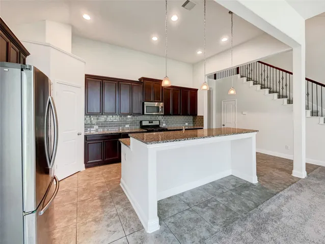 a kitchen with granite countertop a refrigerator and a sink