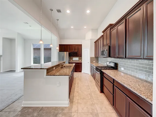 a kitchen with stainless steel appliances granite countertop wooden cabinets a stove and a sink