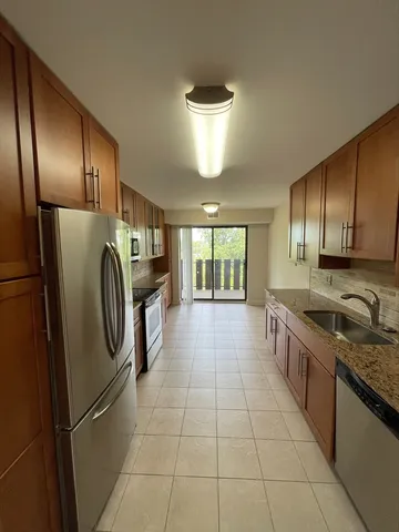 a kitchen with stainless steel appliances granite countertop a refrigerator a sink a stove and cabinets