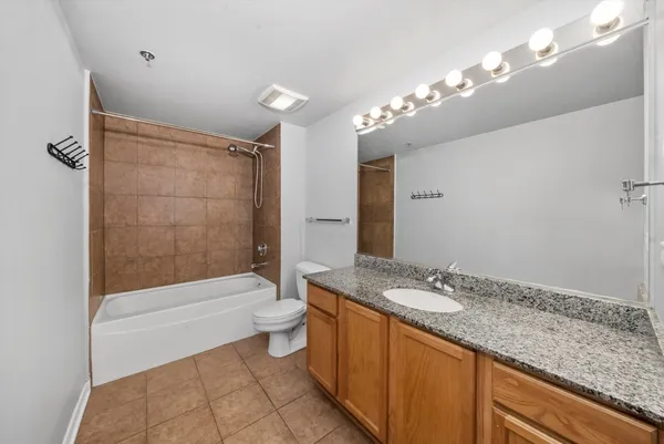 a bathroom with a granite countertop sink a toilet a mirror a bathtub and shower