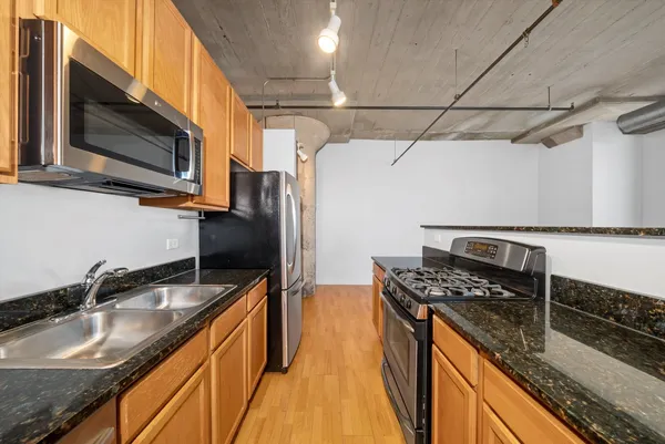a kitchen with granite countertop stainless steel appliances a sink stove top oven and refrigerator