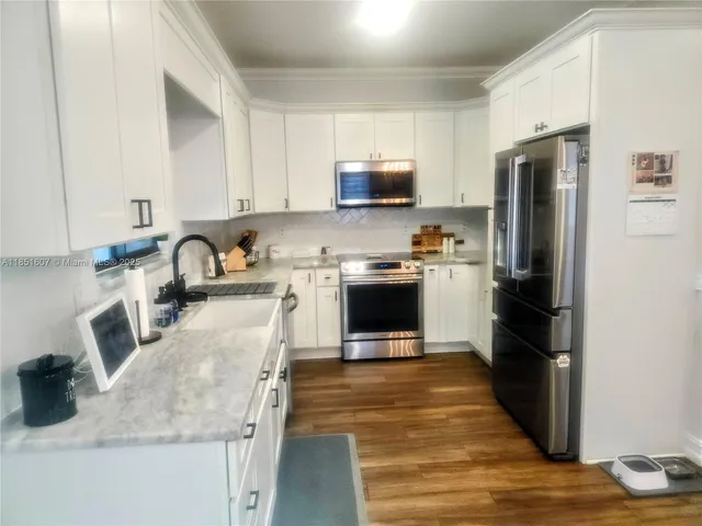 a kitchen with granite countertop a refrigerator stove and sink
