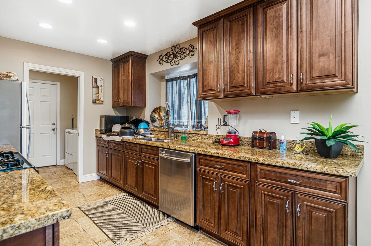 5644 Schooner Loop Discovery Bay, CA 94505 - Photo 13 of 42 a kitchen with stainless steel appliances granite countertop a sink dishwasher stove and refrigerator with wooden cabinets