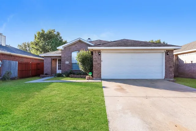 a front view of house with yard and trees in the background