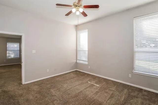 an empty room with windows and fan
