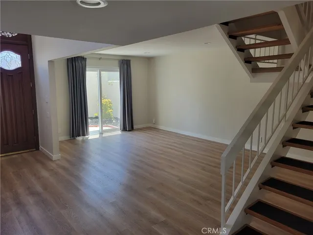 a view of an empty room with wooden floor and stairs