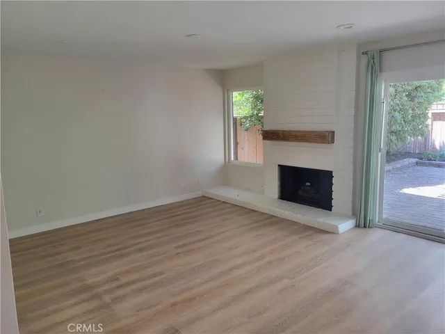 a view of empty room with wooden floor and fireplace