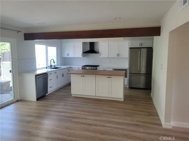 a kitchen with stainless steel appliances granite countertop a stove top oven a sink and a refrigerator