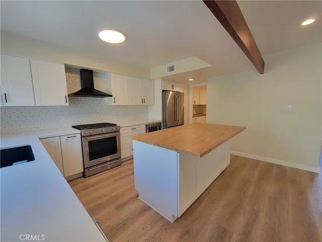 a kitchen with stainless steel appliances kitchen island granite countertop a stove a sink and a refrigerator