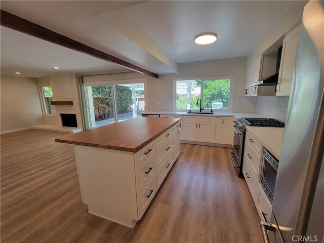 a kitchen with granite countertop a sink appliances wooden floor and cabinets