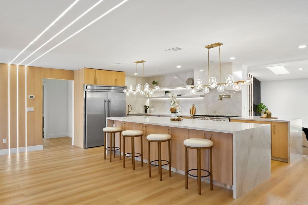 a kitchen with stainless steel appliances granite countertop a table chairs sink and wooden floor