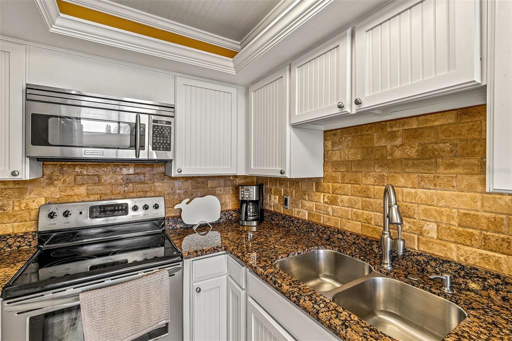 9495 Blind Pass Road, Unit 202 St. Pete Beach, FL 33706 - Photo 14 of 55 a kitchen with granite countertop a sink stainless steel appliances and cabinets