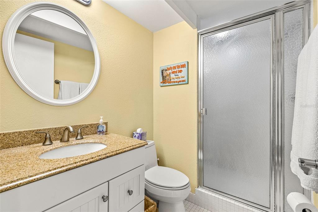 9495 Blind Pass Road, Unit 202 St. Pete Beach, FL 33706 - Photo 23 of 55 a bathroom with a granite countertop sink toilet and a mirror