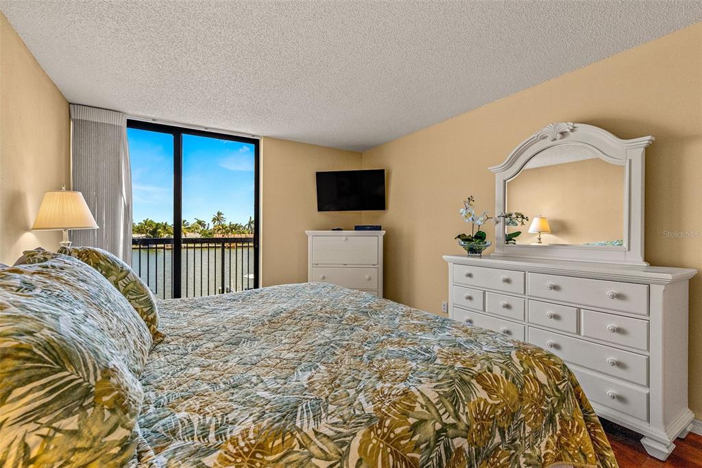 9495 Blind Pass Road, Unit 202 St. Pete Beach, FL 33706 - Photo 4 of 55 a bedroom with a bed and a dresser with mirror
