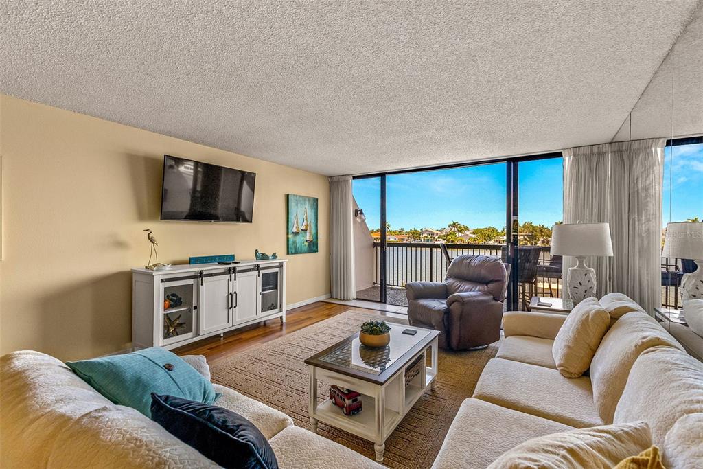 9495 Blind Pass Road, Unit 202 St. Pete Beach, FL 33706 - Photo 6 of 55 a living room with furniture and a flat screen tv