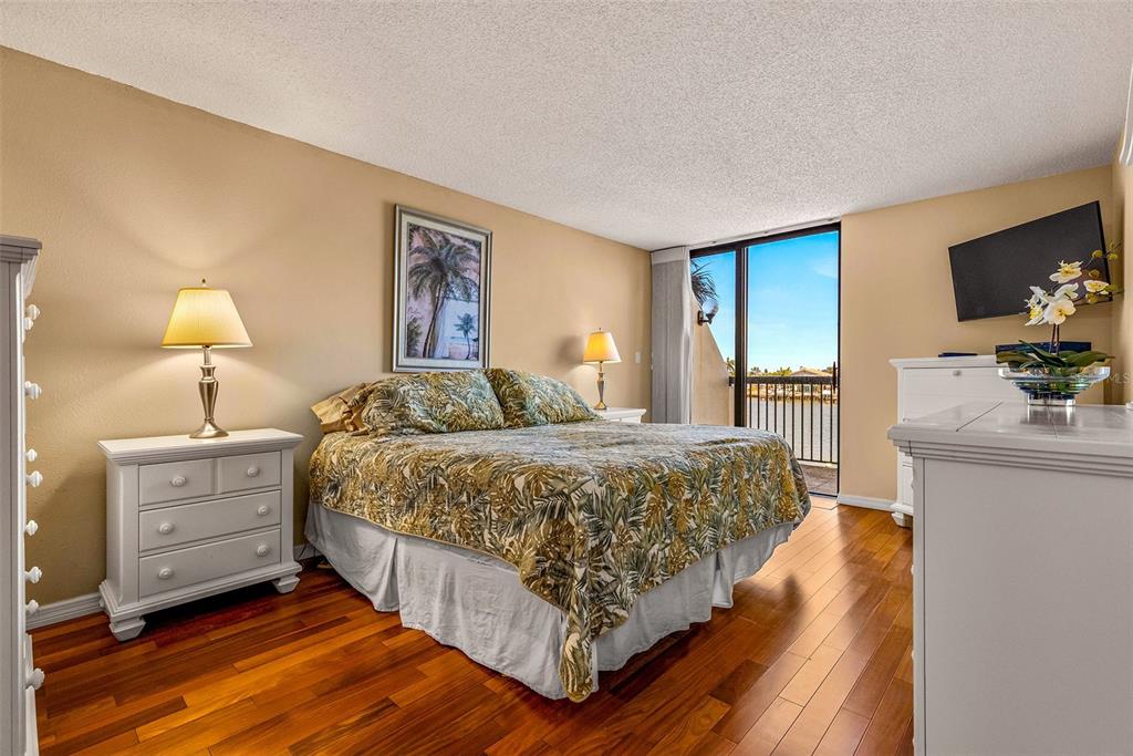 9495 Blind Pass Road, Unit 202 St. Pete Beach, FL 33706 - Photo 9 of 55 a bedroom with a bed and a flat screen television