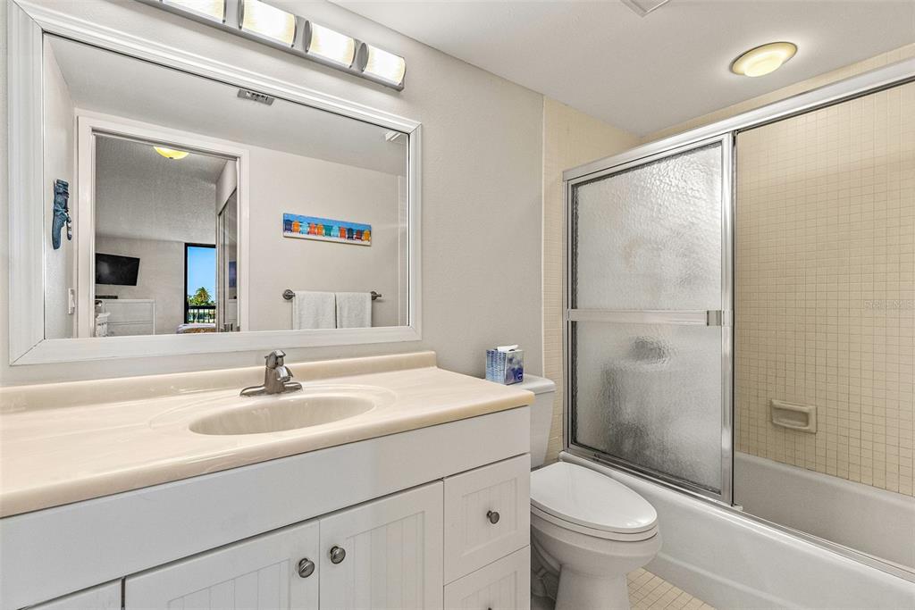 9495 Blind Pass Road, Unit 202 St. Pete Beach, FL 33706 - Photo 10 of 55 a bathroom with a sink a toilet and shower