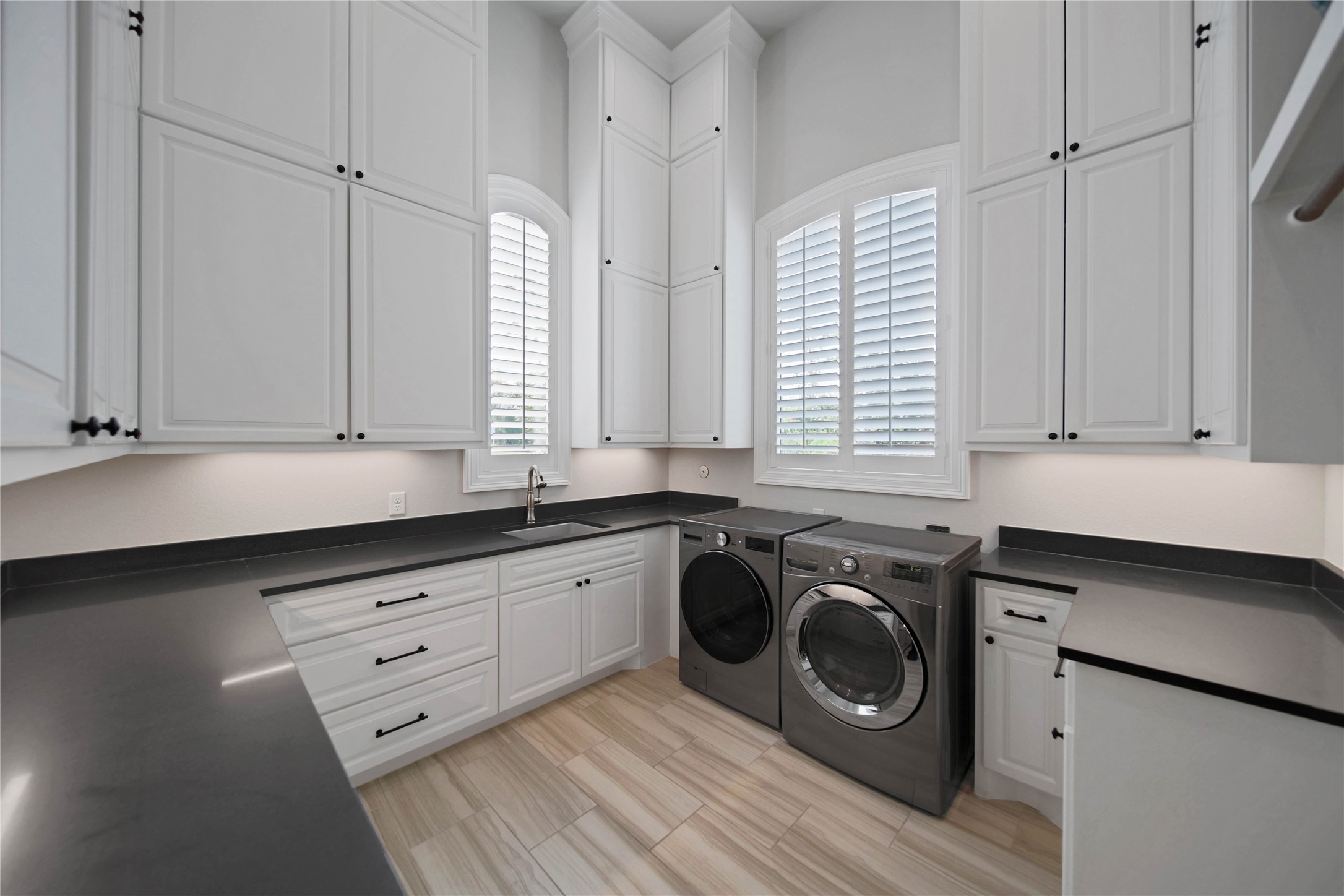24718 Shadow Pond Spring, TX 77389 - Photo 34 of 49 Elegant laundry room with ample white cabinetry, sleek countertops, and modern appliances, enhanced by large windows for natural light.