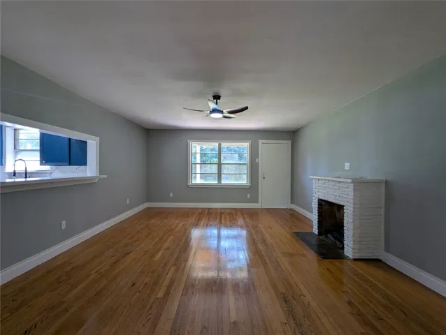 an empty room with wooden floor fireplace and windows