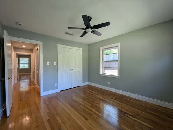 a view of empty room with wooden floor and fan